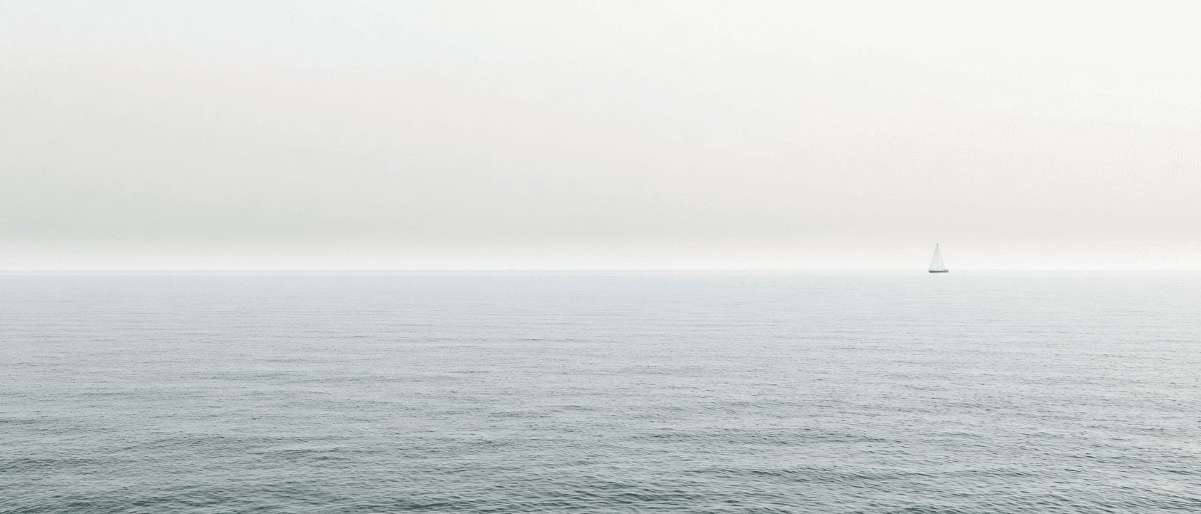 A sailboat drifts across the Lake Ontario horizon seen from the Oakville waterfront.